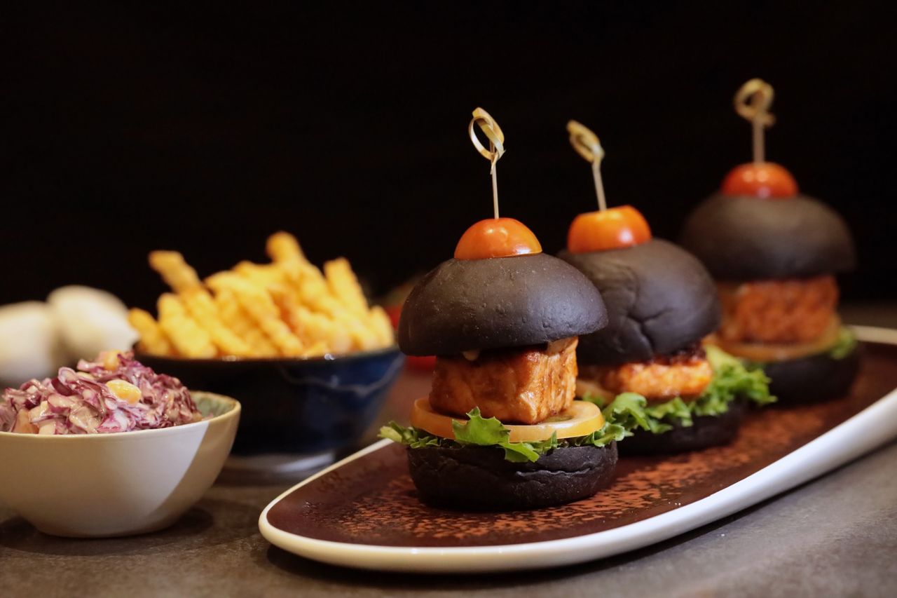 heros-img Appetizing black bun sliders served with fries and coleslaw on a stylish platter.